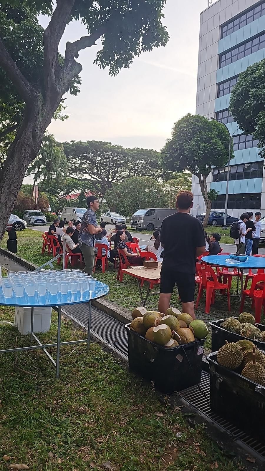 Outdoor corporate durian event setup in Singapore - tables, drinks station and baskets of fresh durian and coconuts
