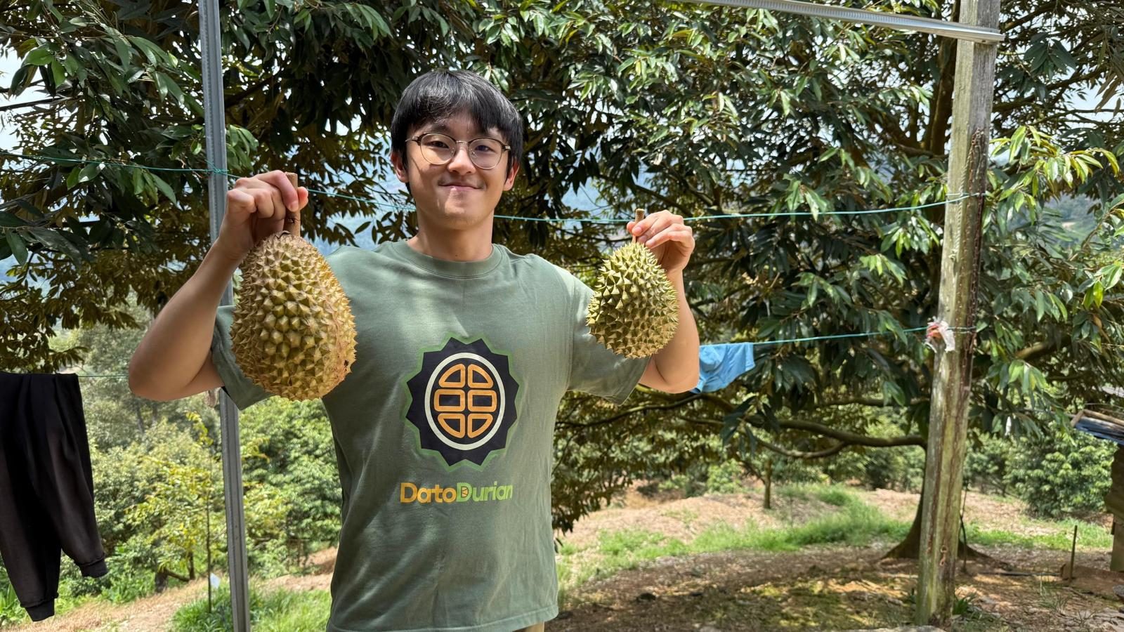 Bobby Sim holding two durians at the DatoDurian farm in Pahang